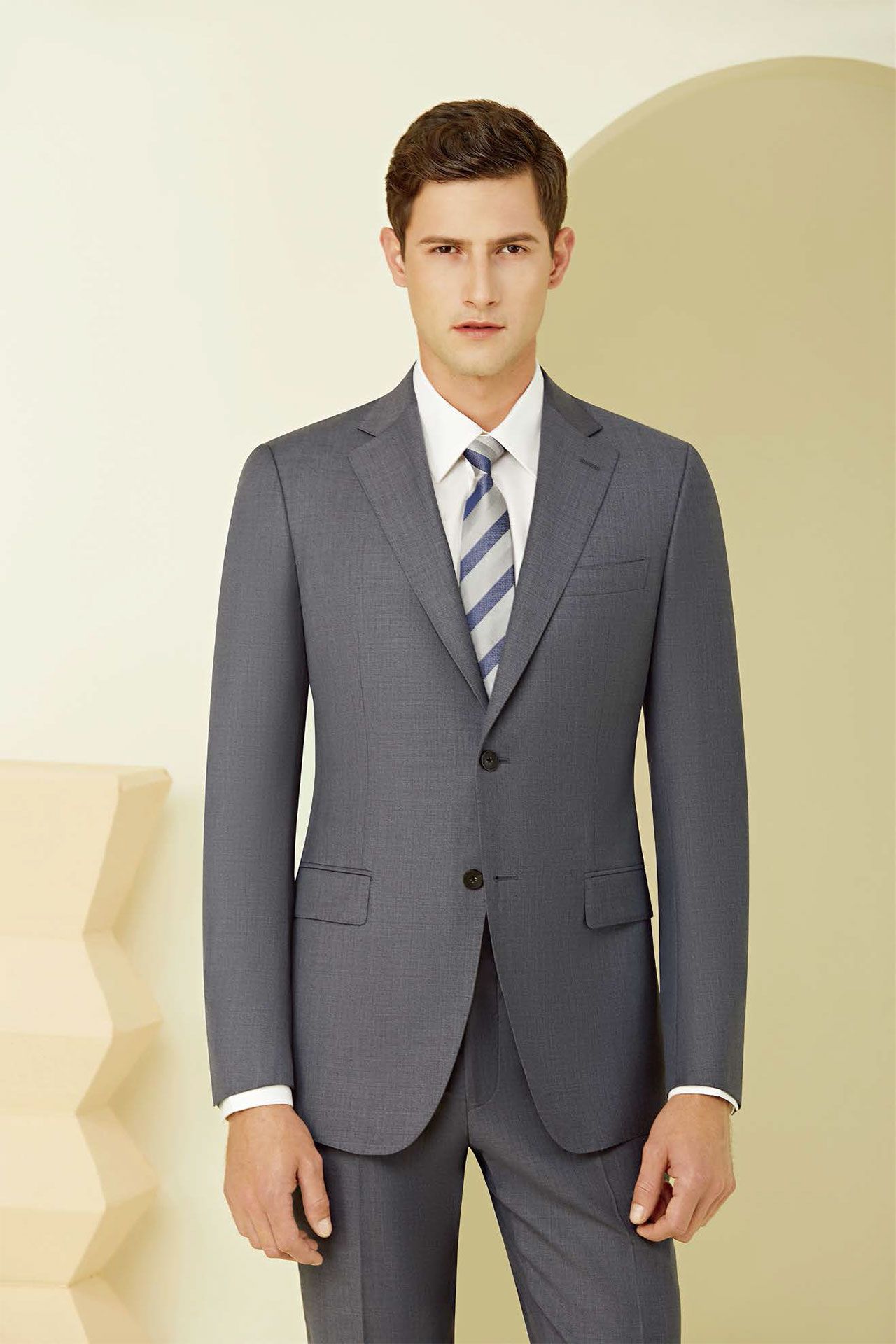 A man in a suit and tie is standing in front of a wall