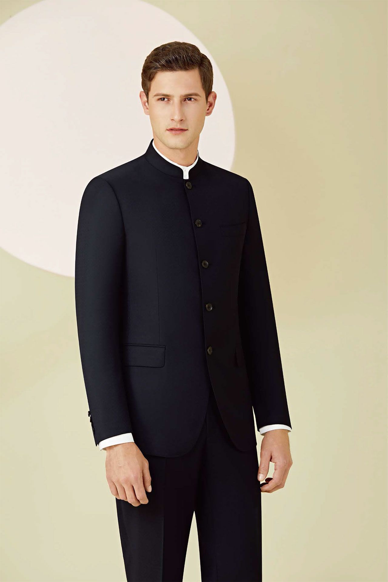 A man is wearing a black suit with a mandarin collar