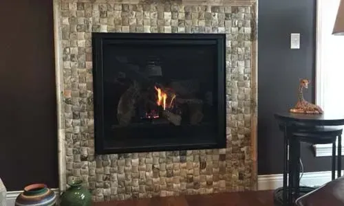 Fireplace with stone tile surround, burning flames. Dark brown walls and black table.
