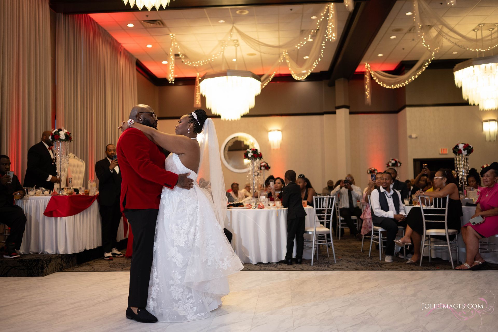 A bride and groom are dancing in a ballroom at their wedding reception.