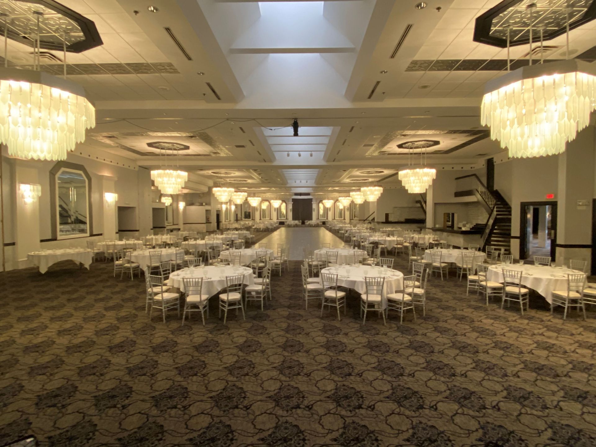 A large ballroom with tables and chairs and chandeliers