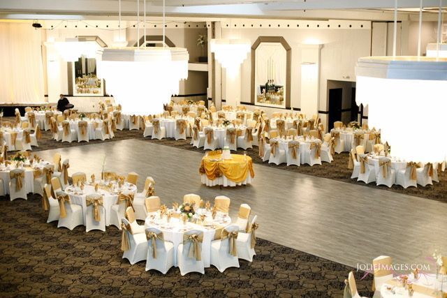A large room with tables and chairs set up for a wedding reception