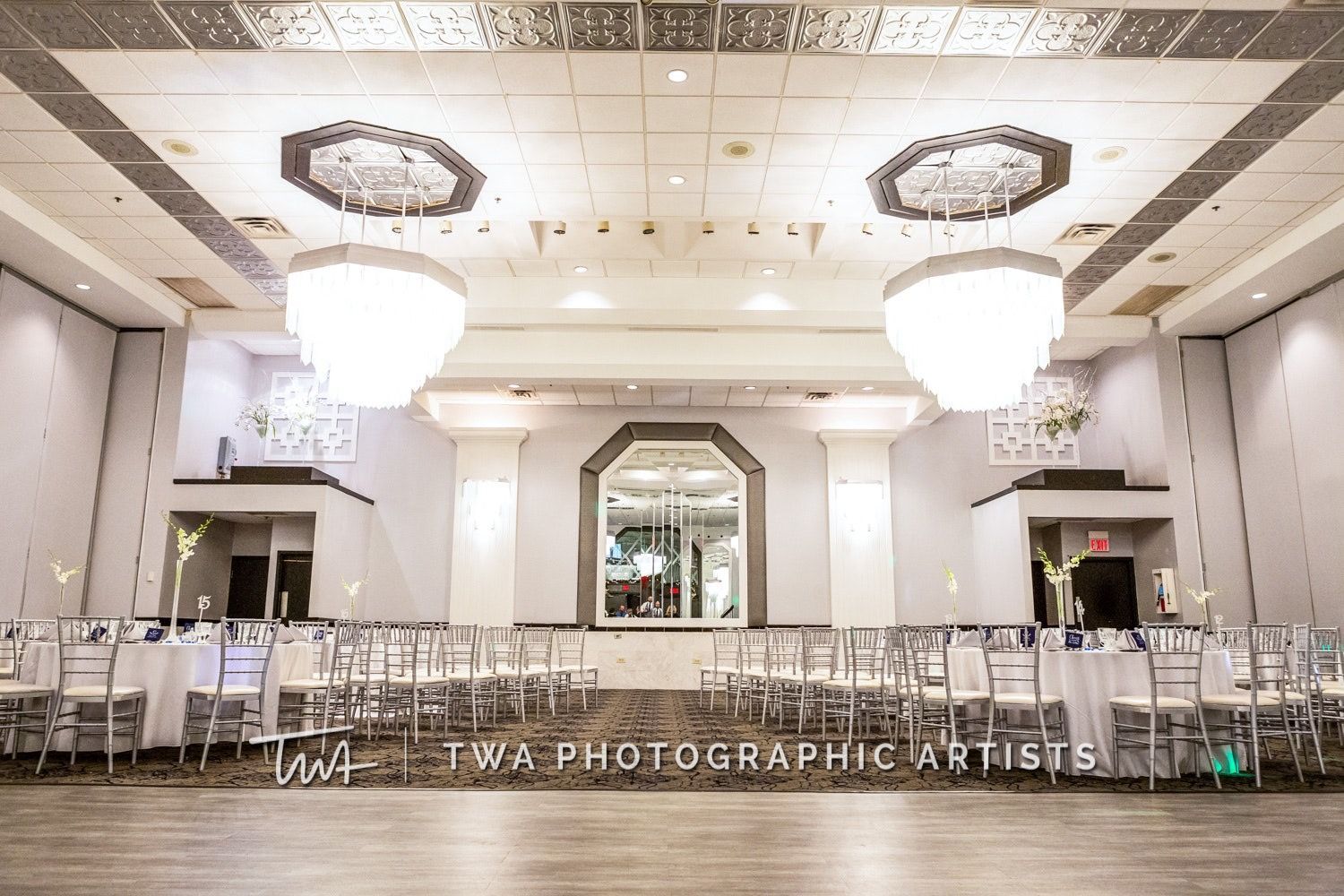 A large ballroom with tables and chairs and chandeliers.