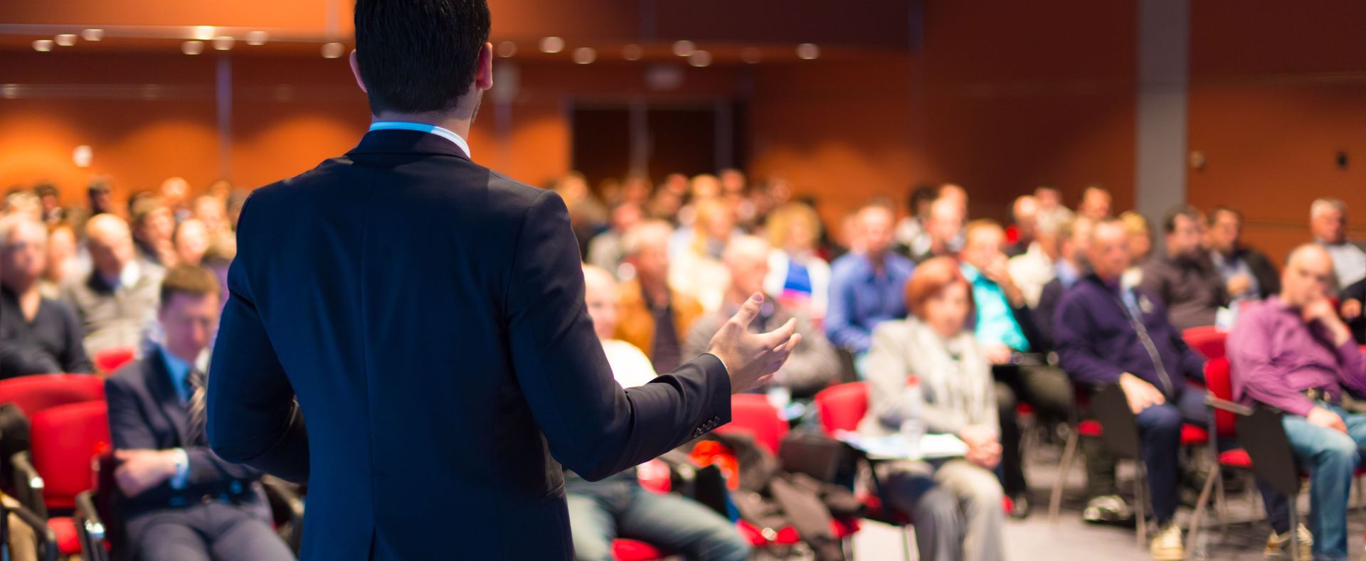 Man giving a presentation to a large audience in a conference room.