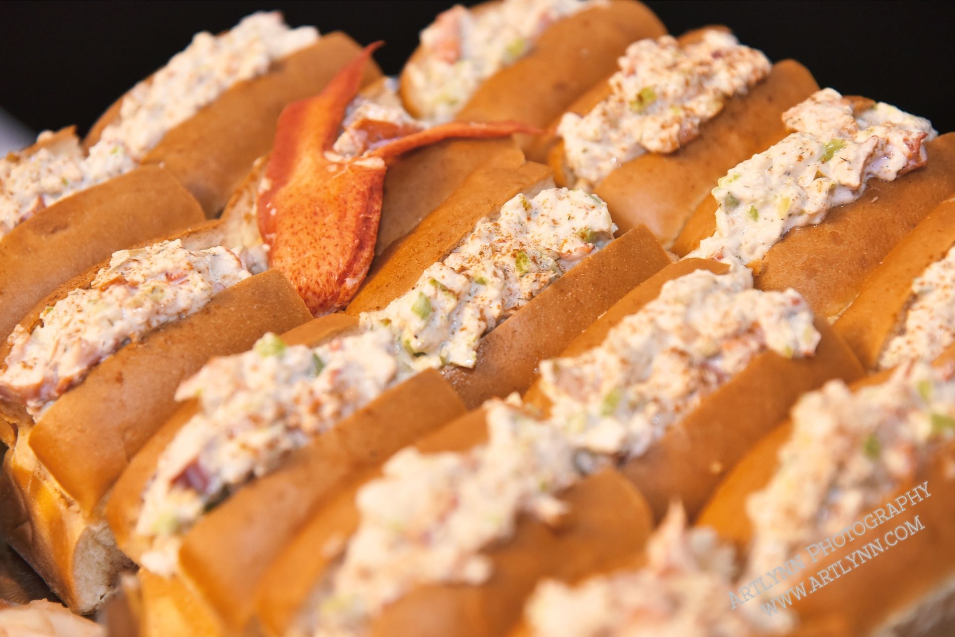 A bunch of lobster rolls with a lobster on top of them.