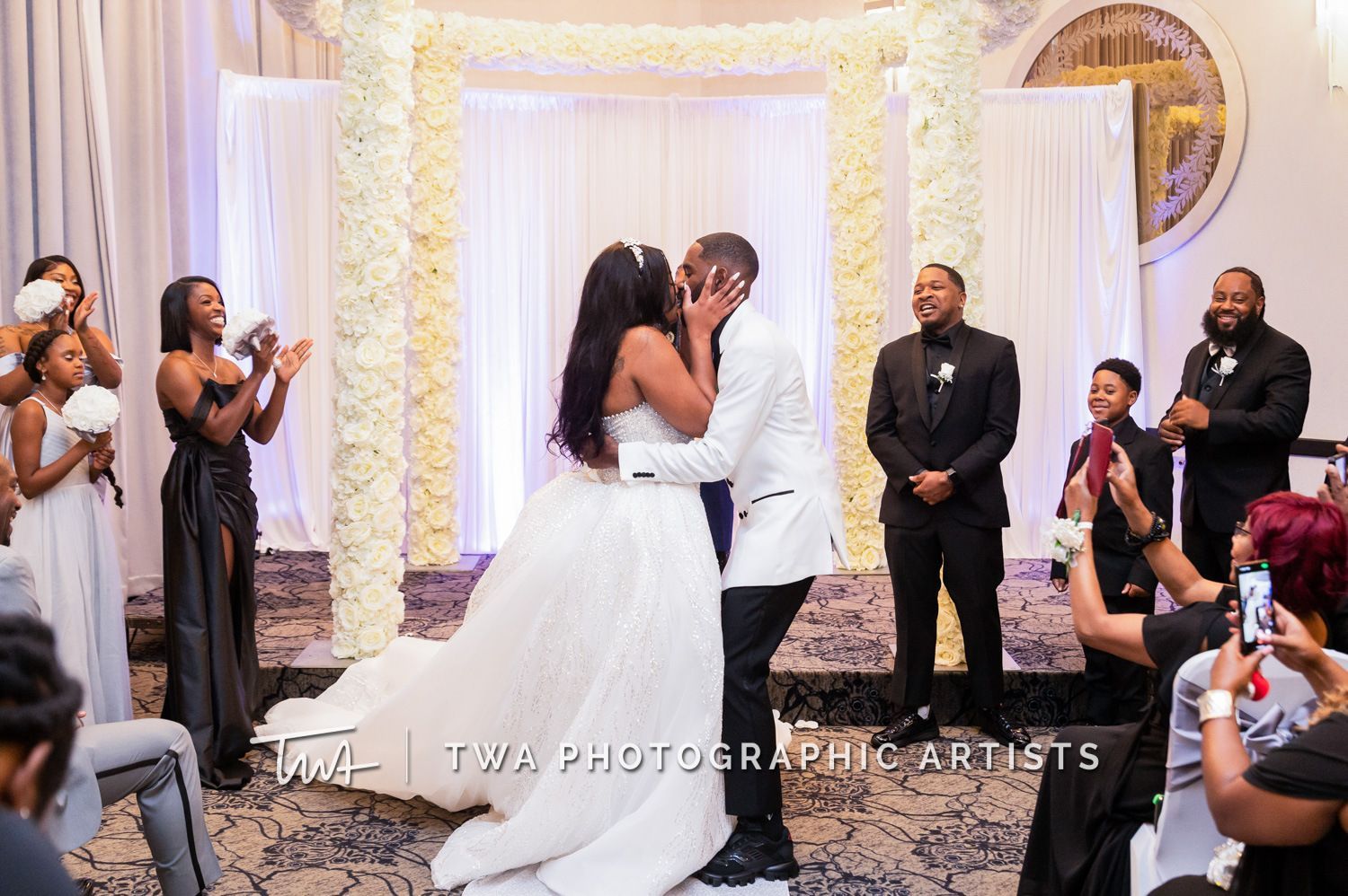 A bride and groom are kissing during their wedding ceremony.