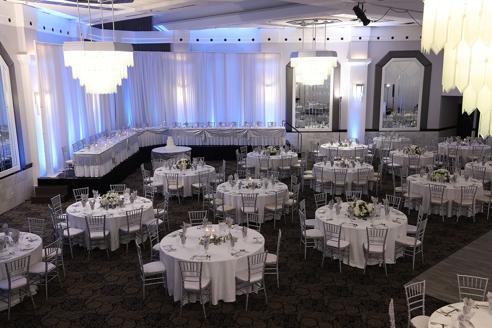 A large room with tables and chairs set up for a wedding reception