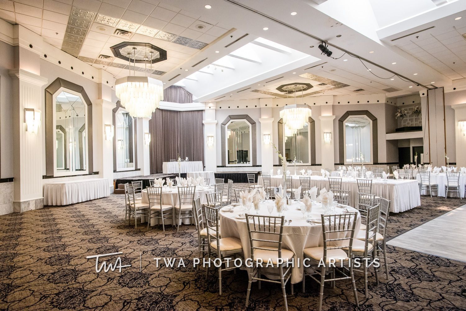 A large ballroom with tables and chairs set up for a wedding reception.
