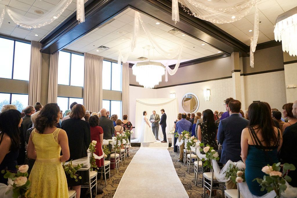 A large group of people are watching a wedding ceremony in a large room.