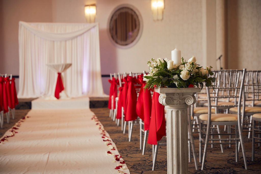 A wedding ceremony is being held in a room with red and white decorations.
