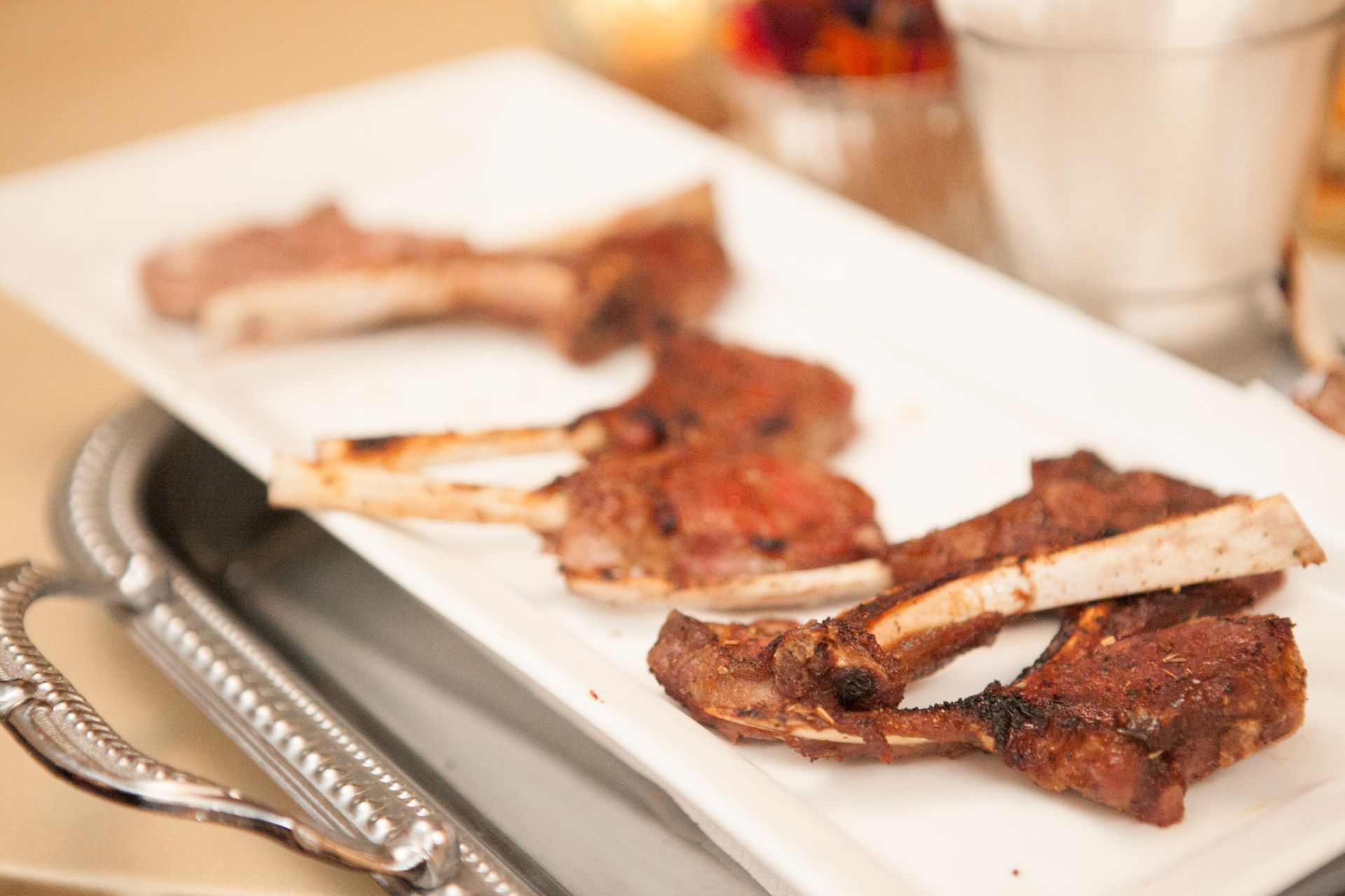 Lamb chops on a white rectangular platter, served at a table setting.