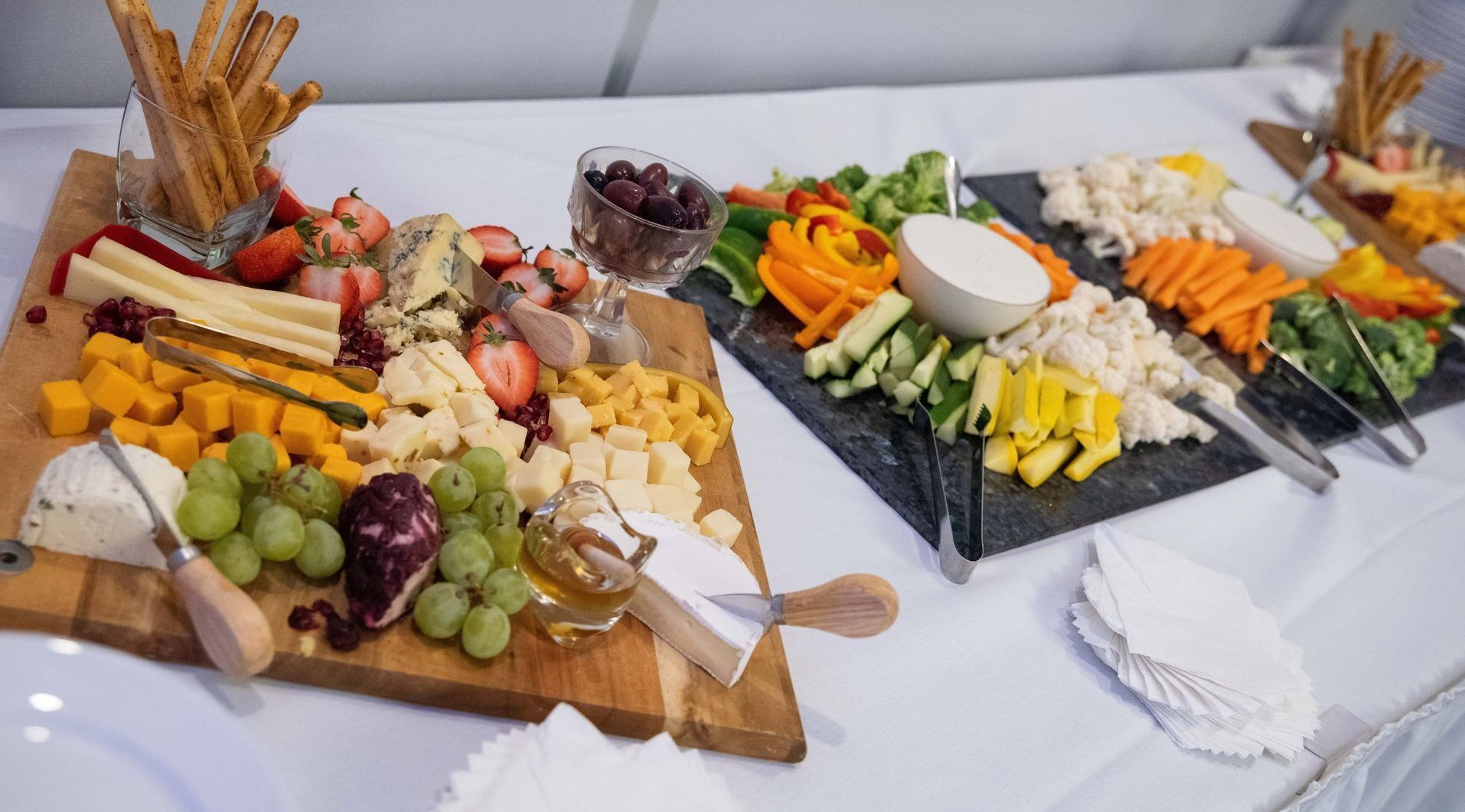 A table spread with cheese, fruits, vegetables, crackers, and dips.