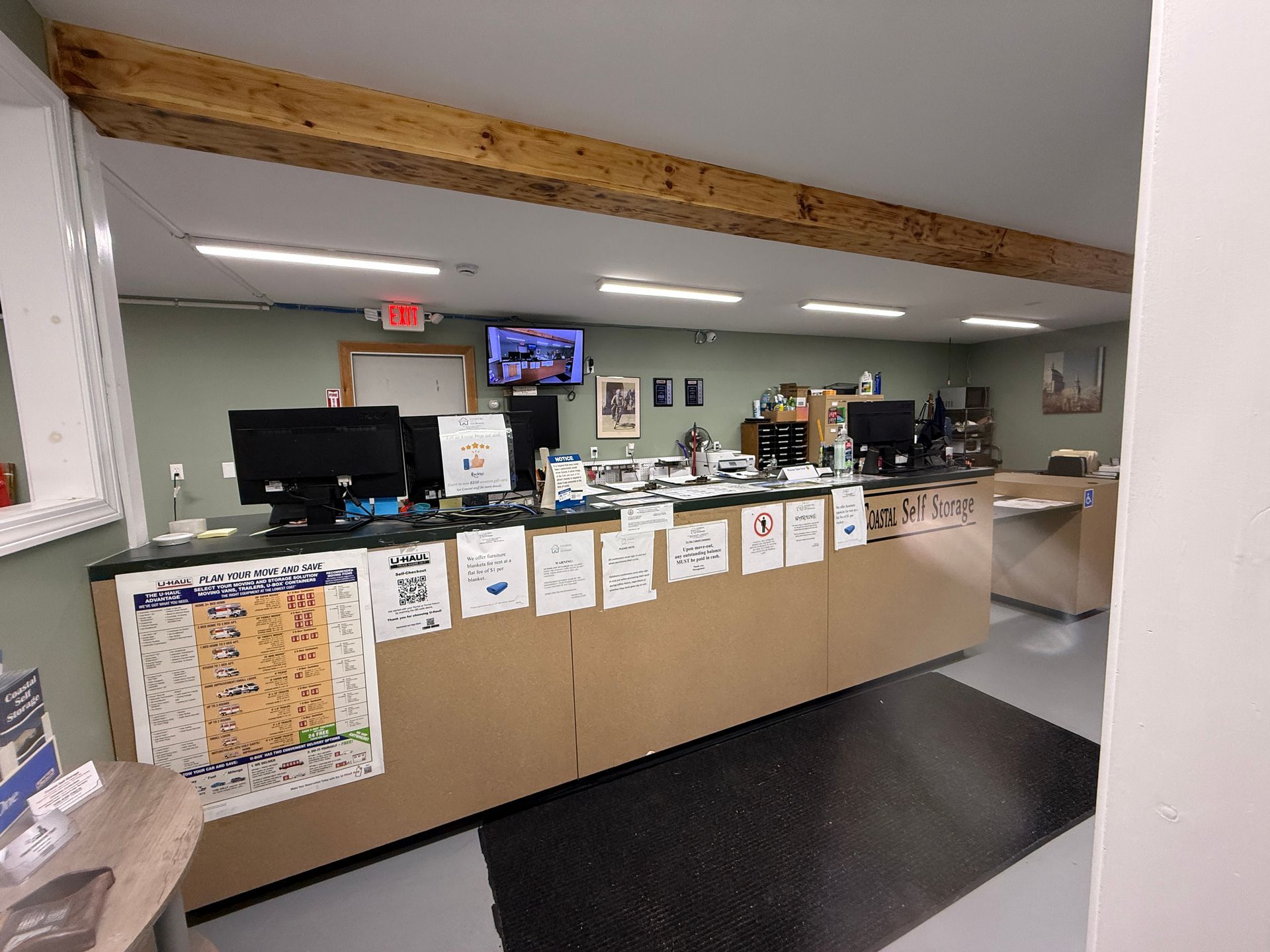 Interior of a business office with a long counter, computers, and overhead beam.