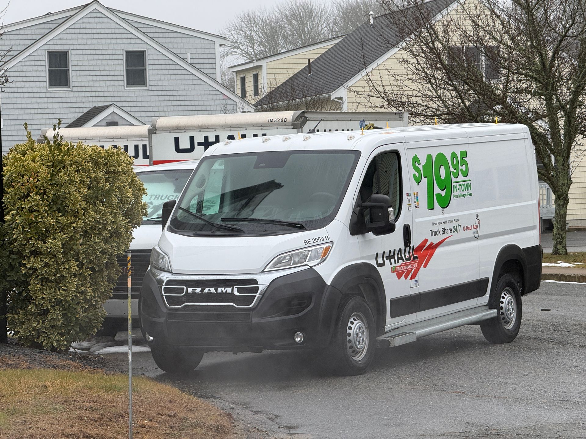 U-Haul van, white with red logo, parked near a building. 