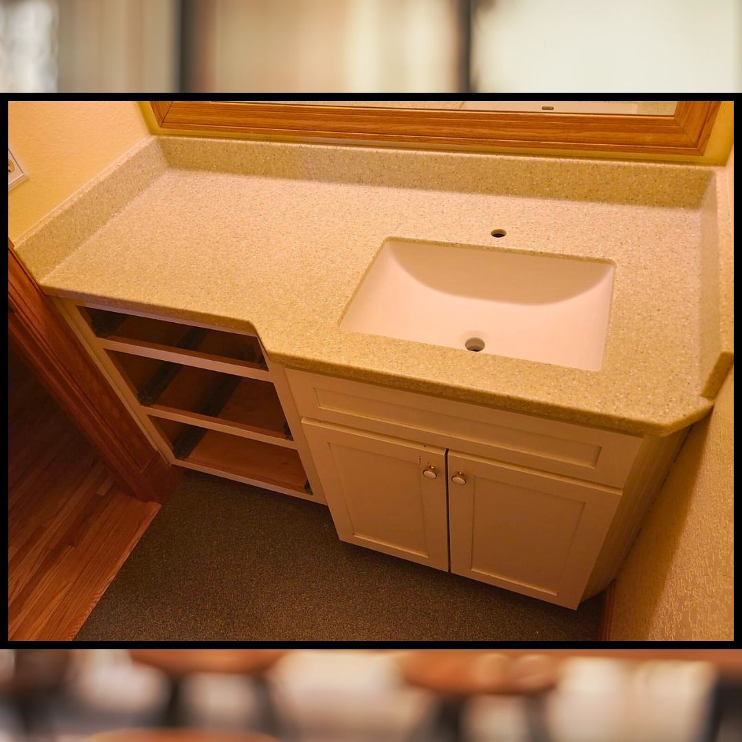 Bathroom vanity with cream-colored countertop, white sink, cabinets, and open shelving. - after