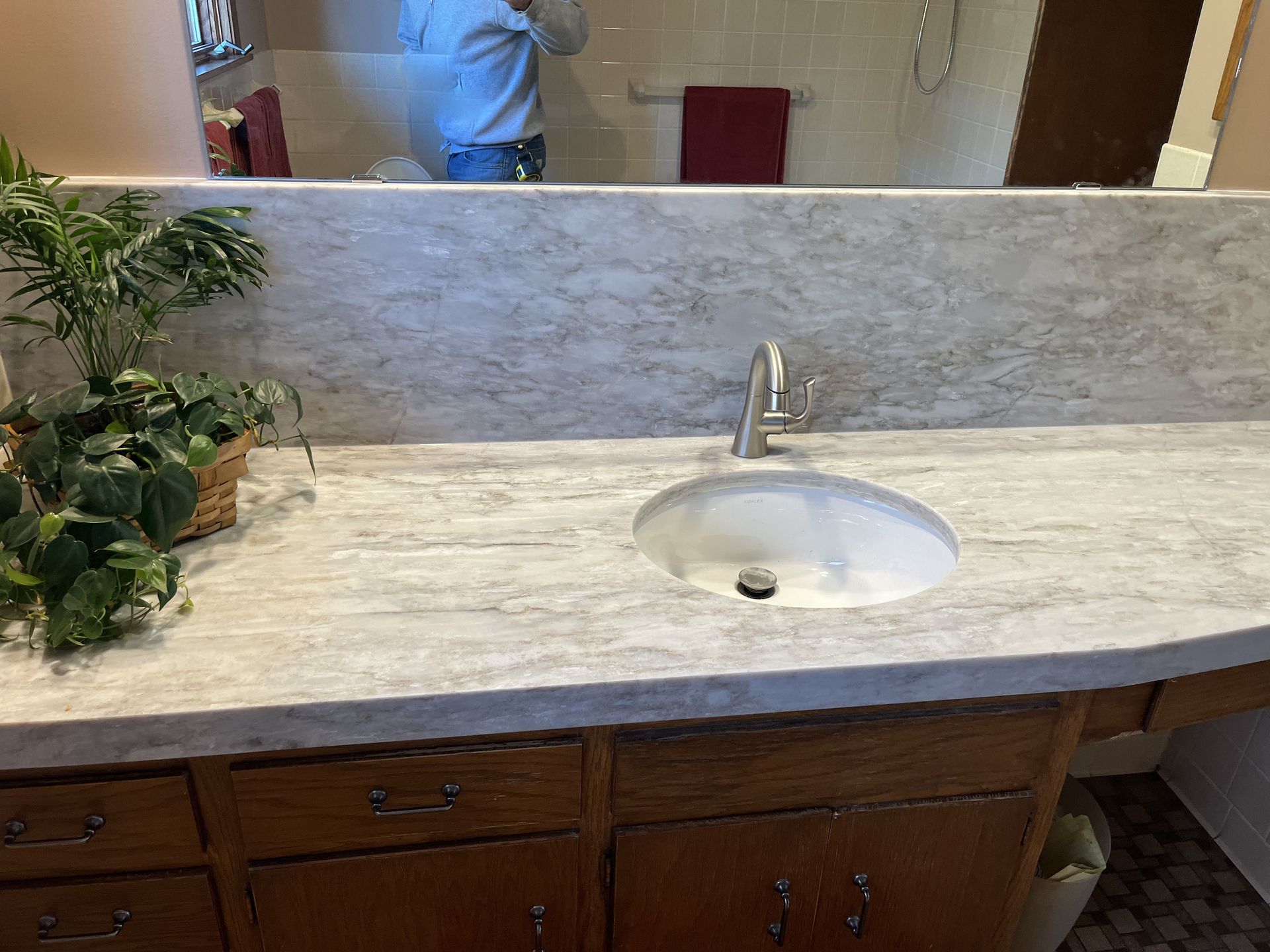 Bathroom vanity with a white sink, gray countertop, and wooden cabinets. - after