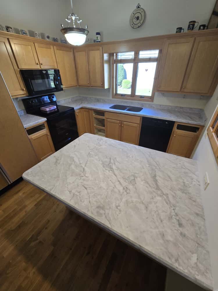 Kitchen with light wood cabinets, gray countertops, and a black stove.