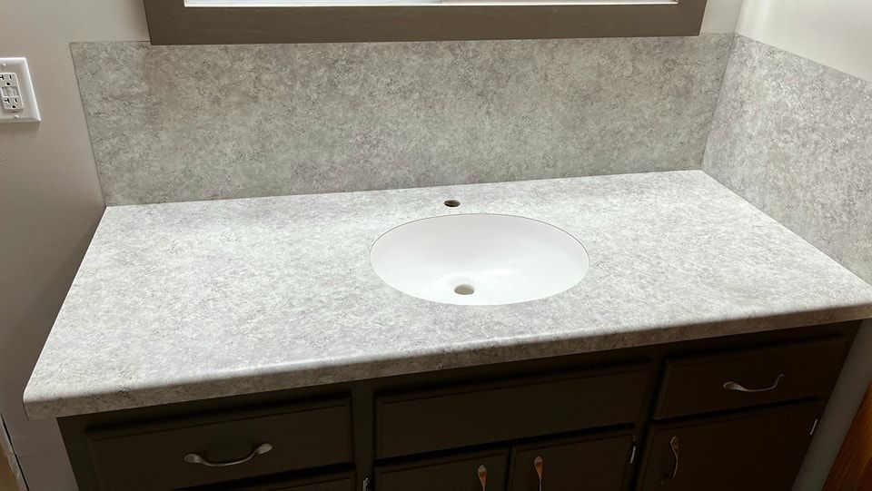Bathroom vanity with gray speckled countertop, white sink, and dark brown cabinets. - after