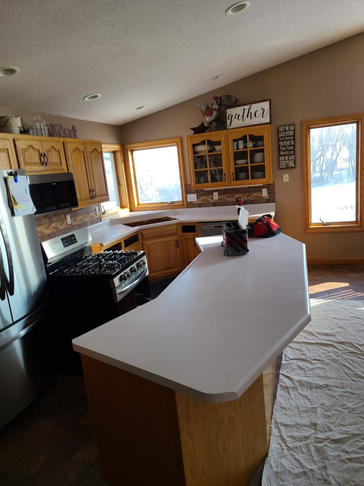 Kitchen with light wood cabinets, white countertops, and stainless steel appliances. - before
