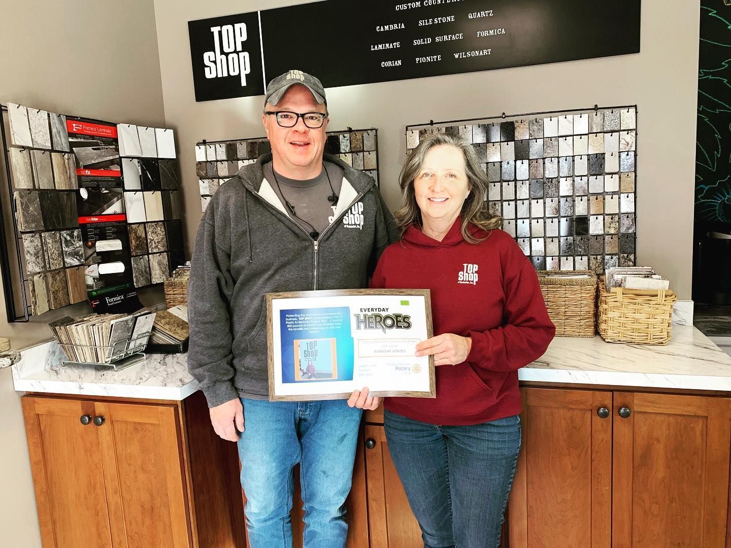 Two people holding an award in a showroom, standing in front of stone samples.
