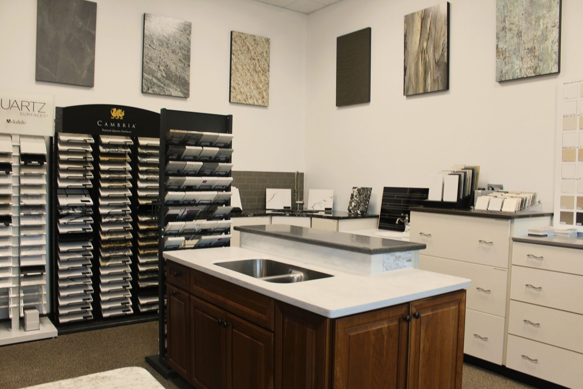 A kitchen showroom with countertop samples on display, including a central island with a sink and cabinets.