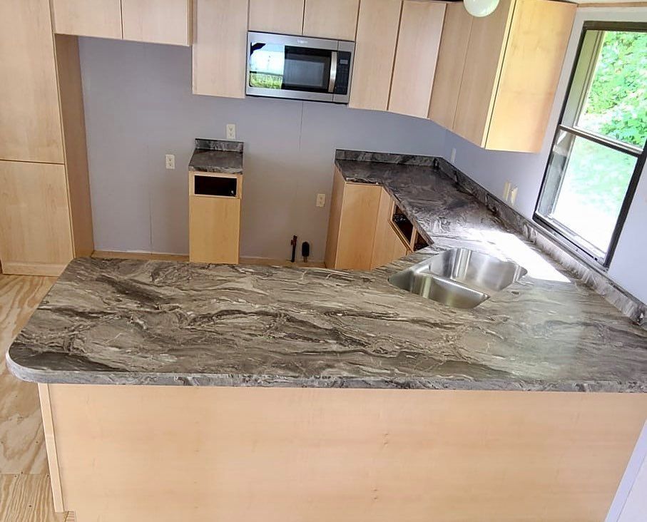 Kitchen with light-colored cabinets and granite countertops; includes a microwave and sink.