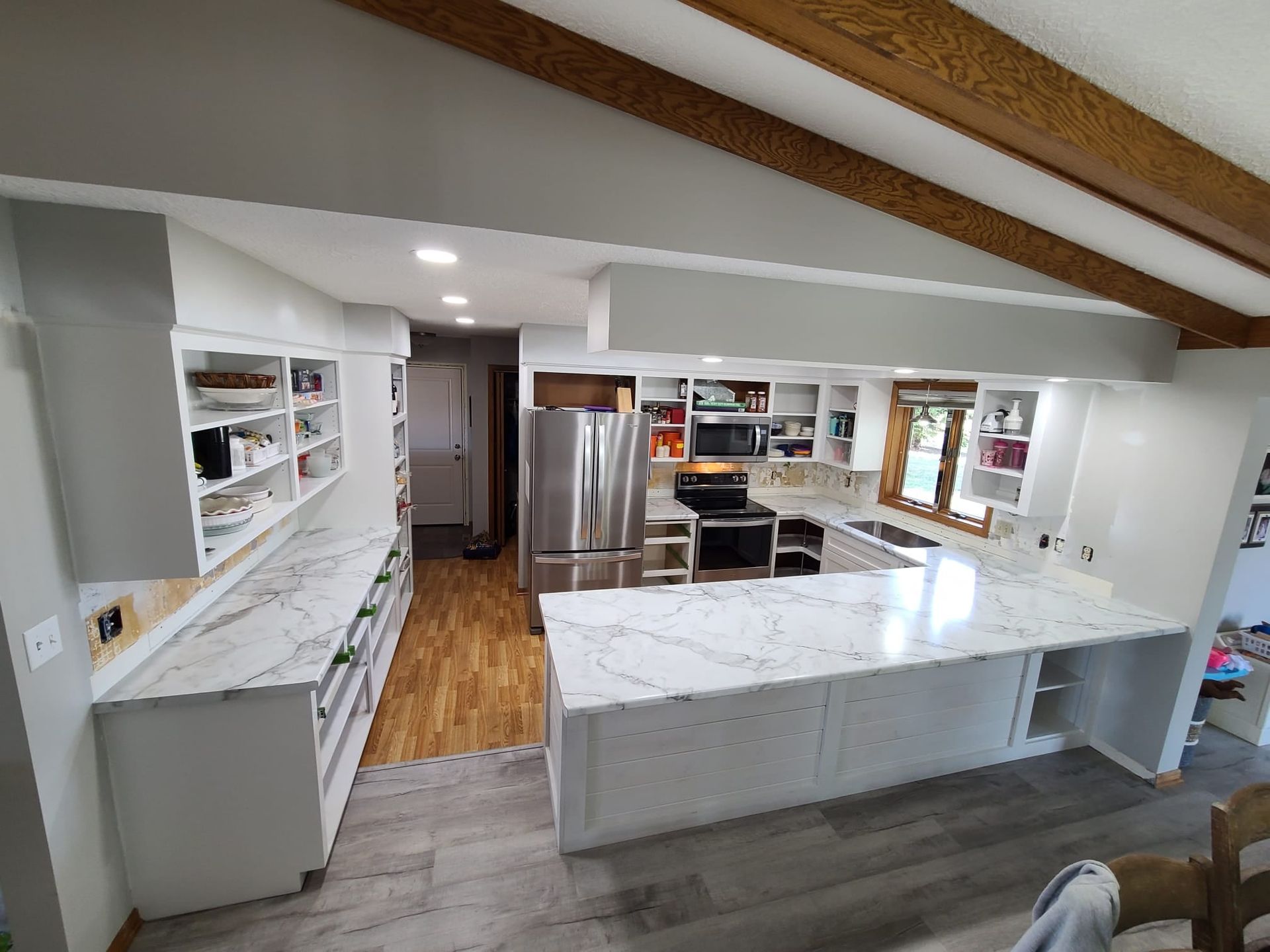 Newly renovated kitchen with white cabinets, marble countertops, and stainless steel appliances.