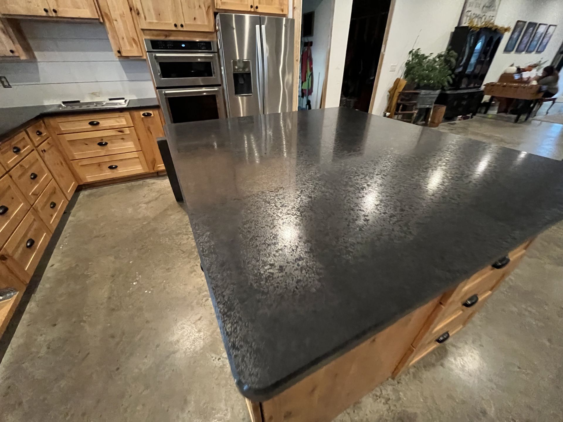 Kitchen with a dark countertop island, stainless steel appliances, and wooden cabinets.