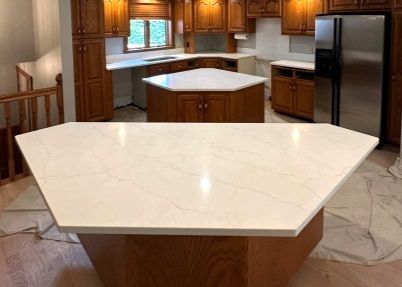 Kitchen remodel with light-colored countertops, wood cabinets, and stainless steel refrigerator.