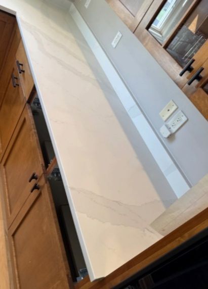 Kitchen: Light-colored countertop and backsplash with a cabinet on the left. Electrical outlets on the wall.