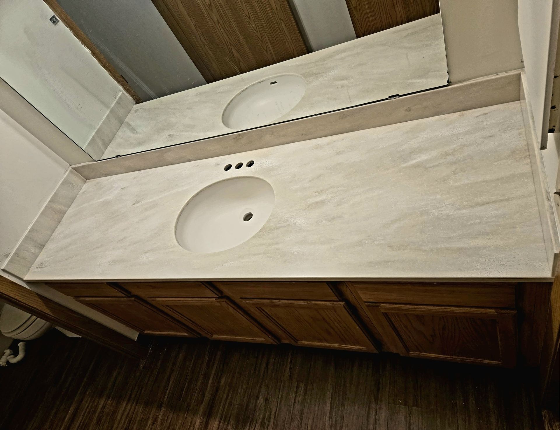 Bathroom vanity with two sinks, light-colored countertop, and dark wood cabinets.
