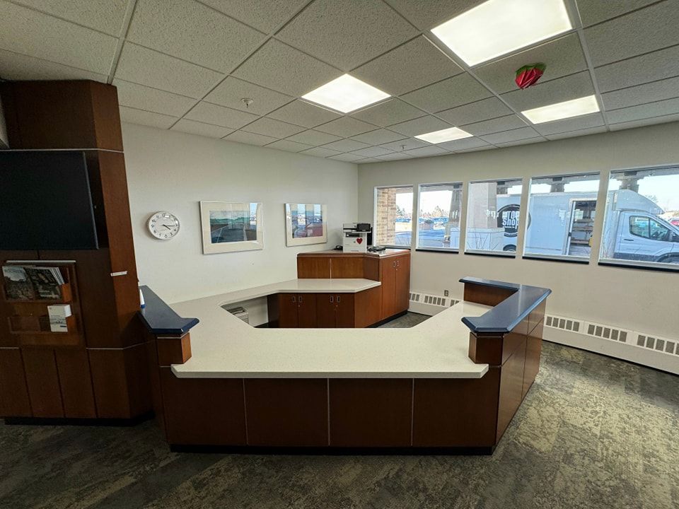 Reception desk in an office with white countertop, dark wood cabinets, and large windows looking outside.