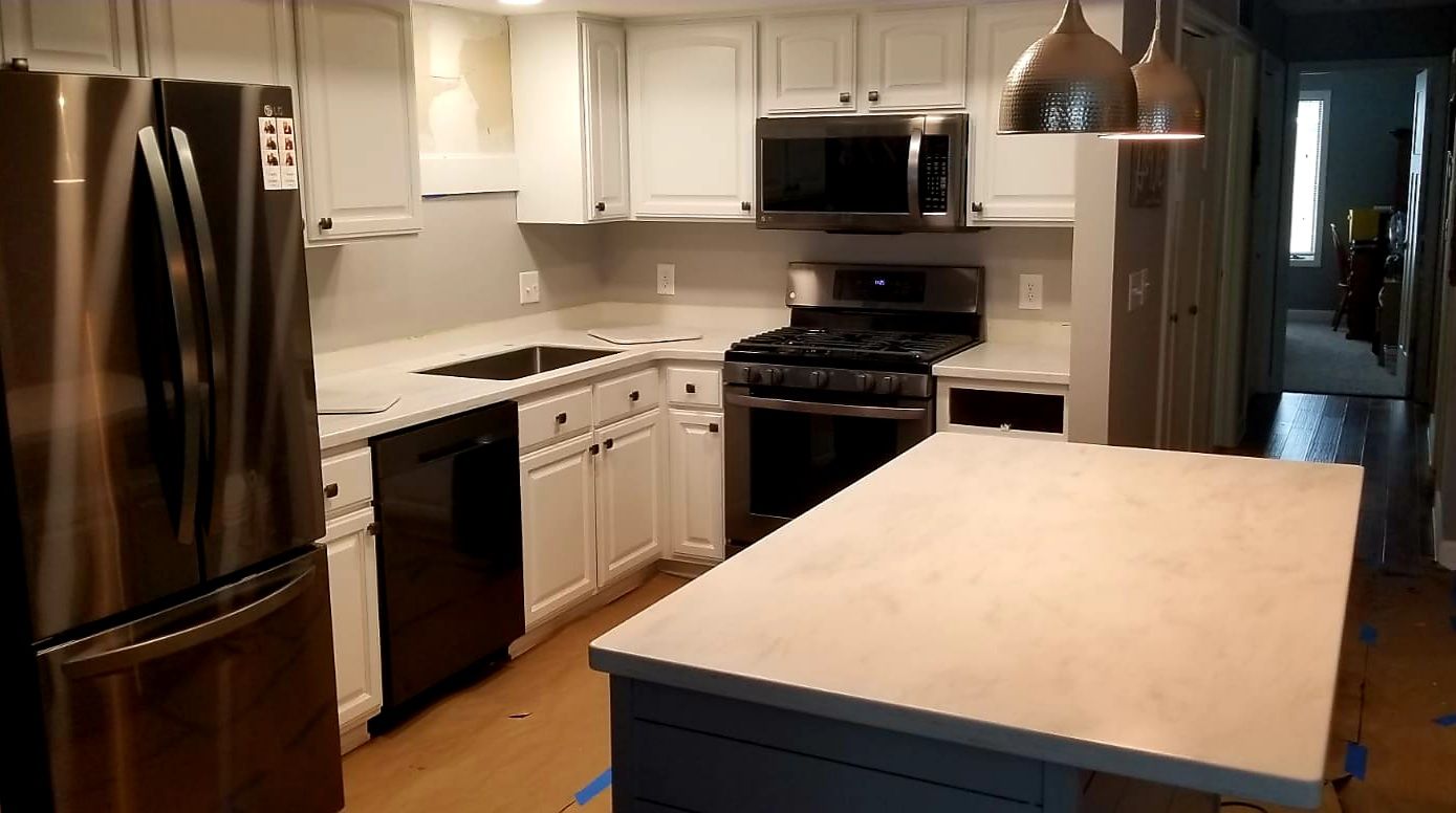 Modern kitchen with white cabinets, stainless steel appliances, and a gray countertop island.