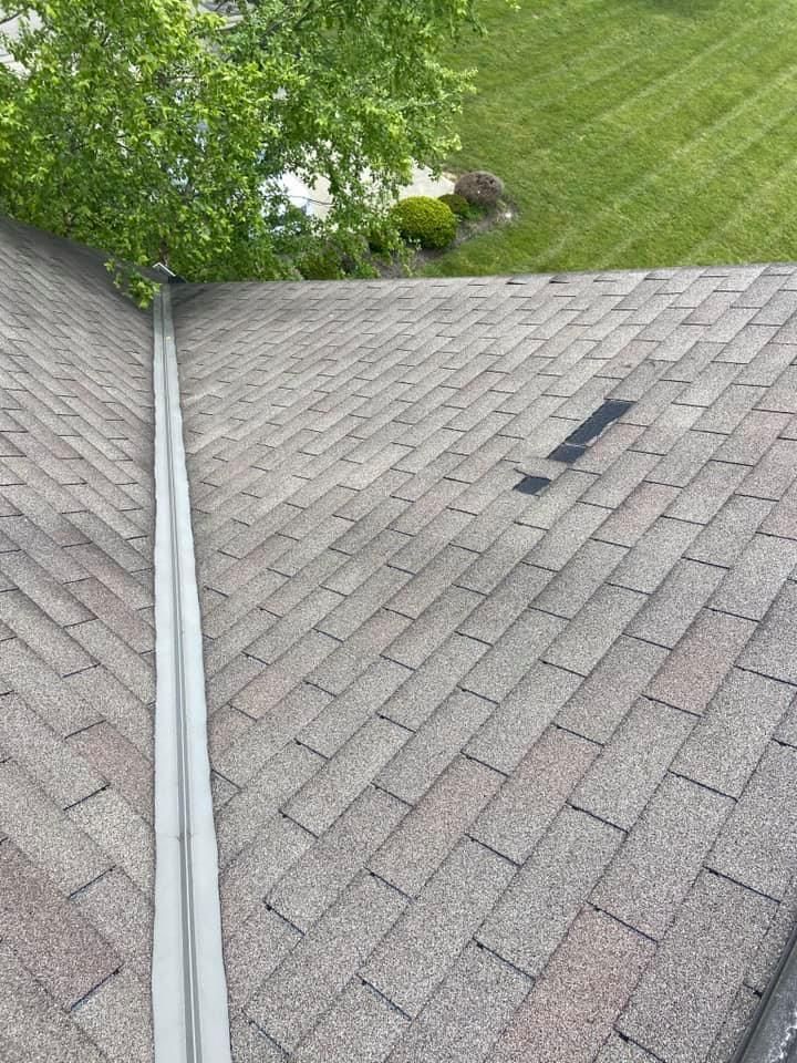 Roof valley with gray shingles, a small dark patch, and green lawn beside it