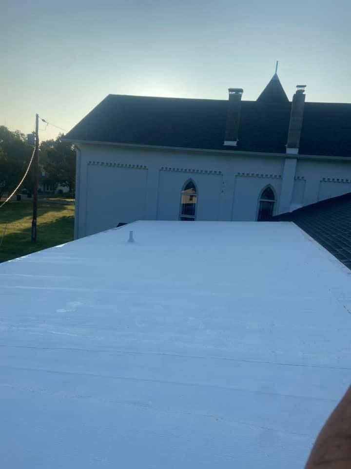 White rooftop in front of a white house at dusk, with a small dormer window and dark roofline.