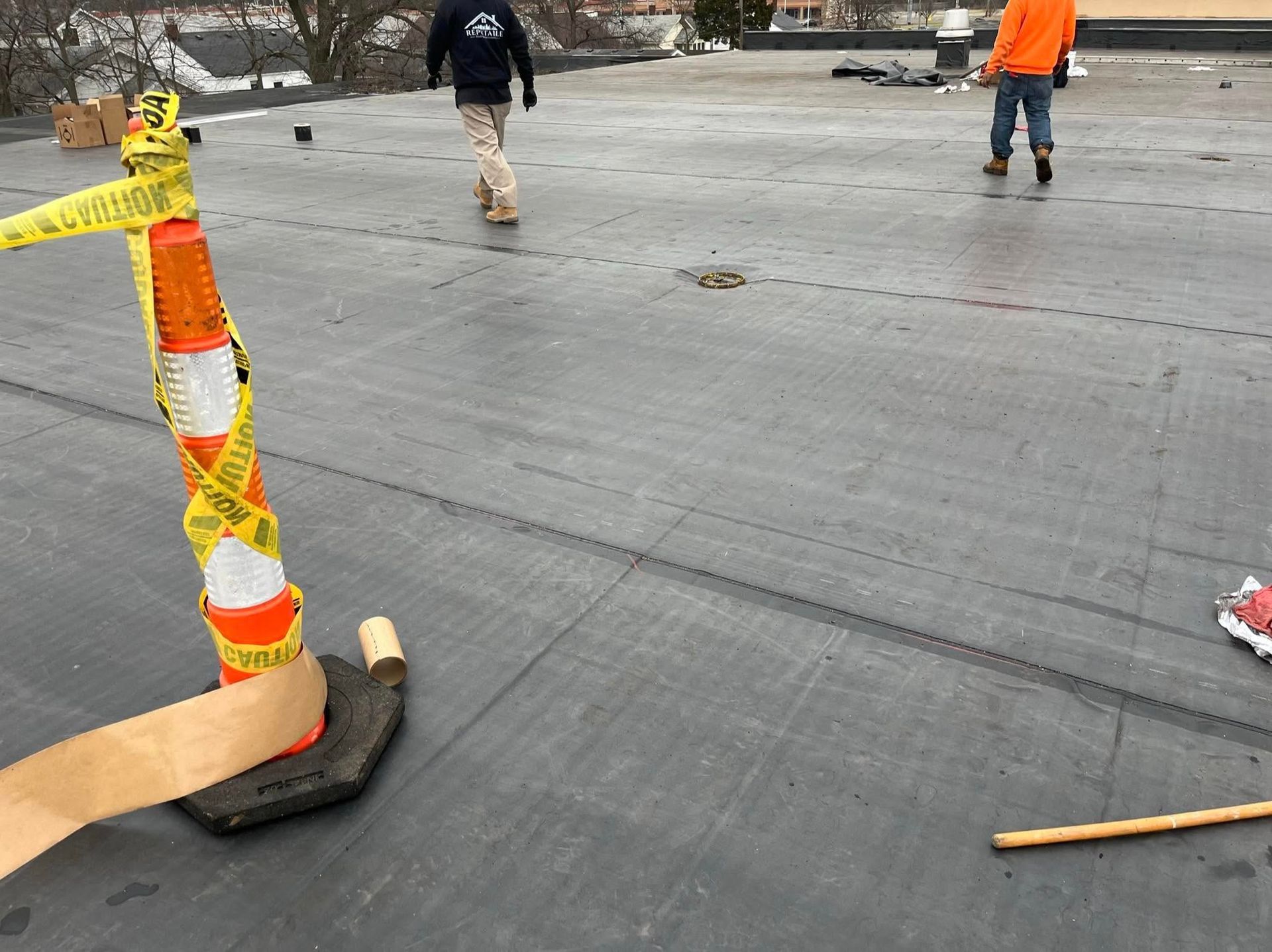 Roadwork scene with workers, orange safety cone, and freshly paved gray pavement