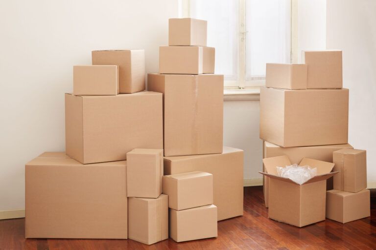 Cardboard moving boxes stacked in a room, some open with packing material.