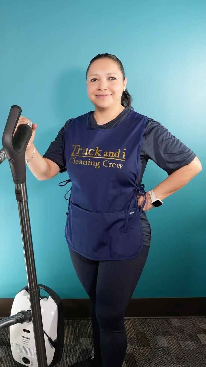 Woman in blue uniform with cleaning equipment, smiling.