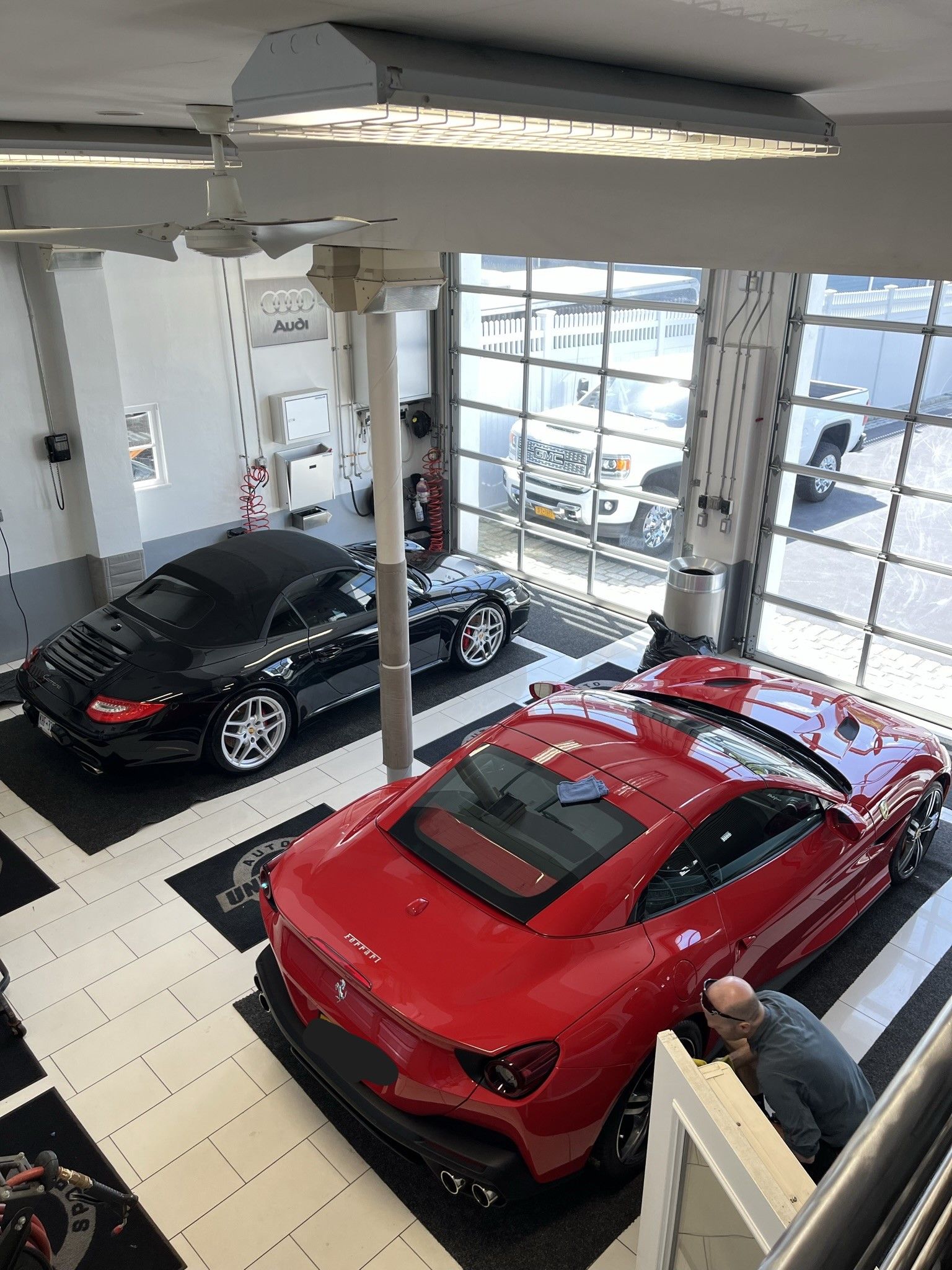 A red car is parked in a showroom next to a black car.