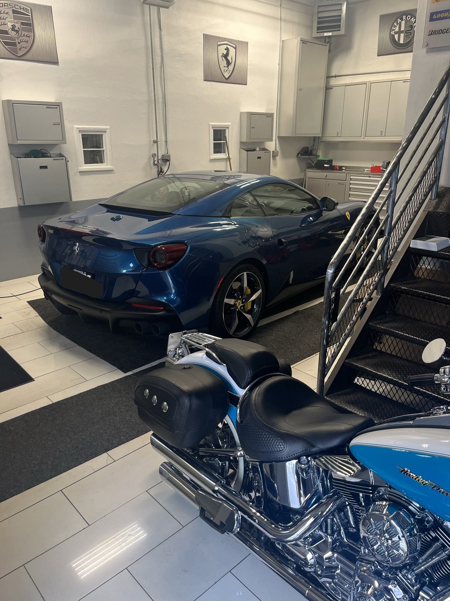 A blue car is parked in a garage next to a motorcycle.