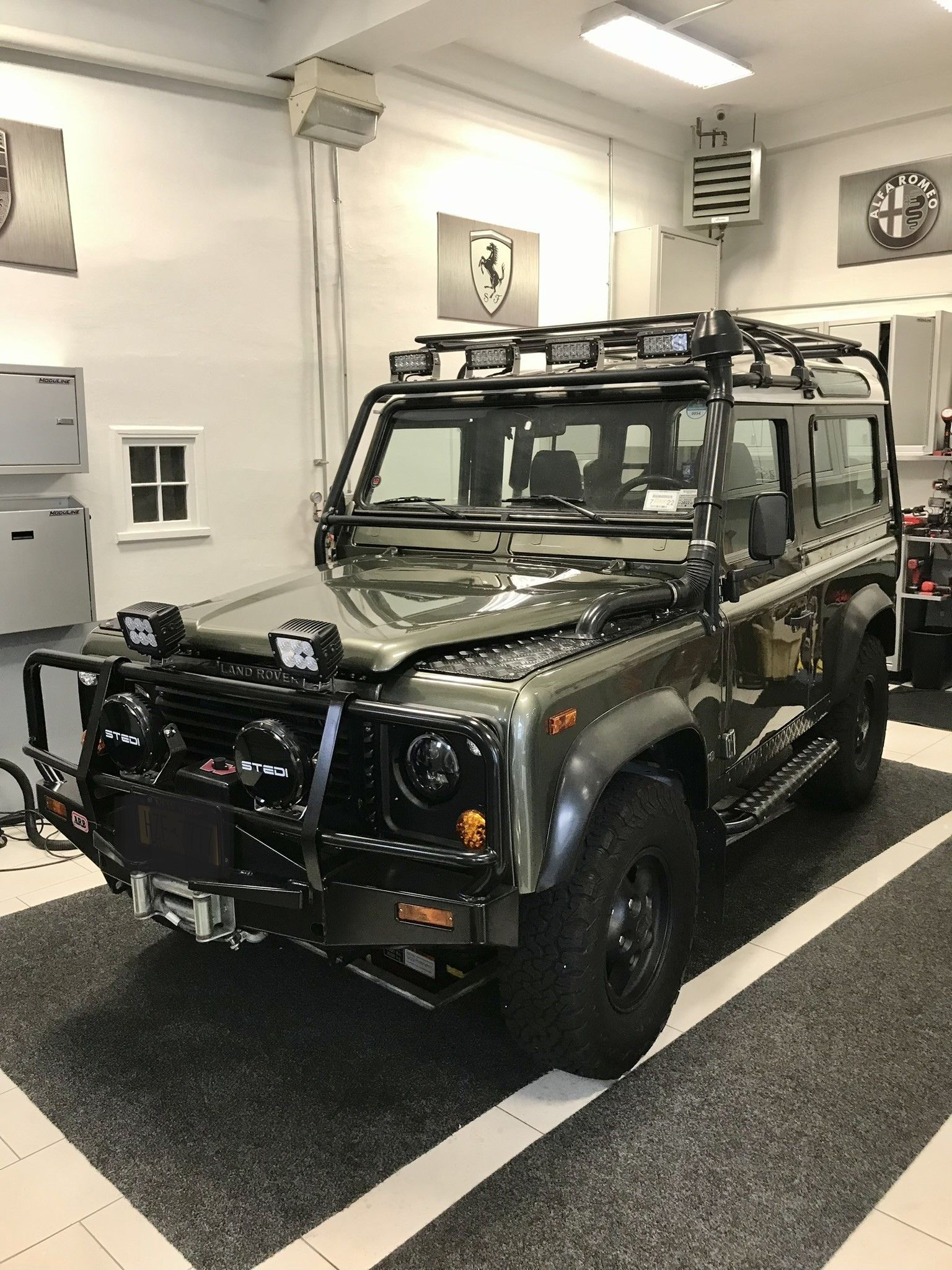 A jeep with a roof rack is parked in a garage.