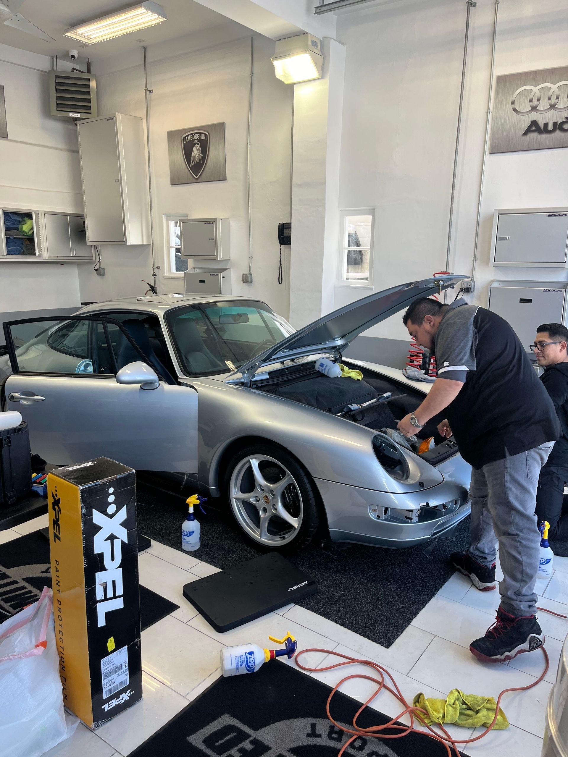 a man is working on a silver car in a garage .