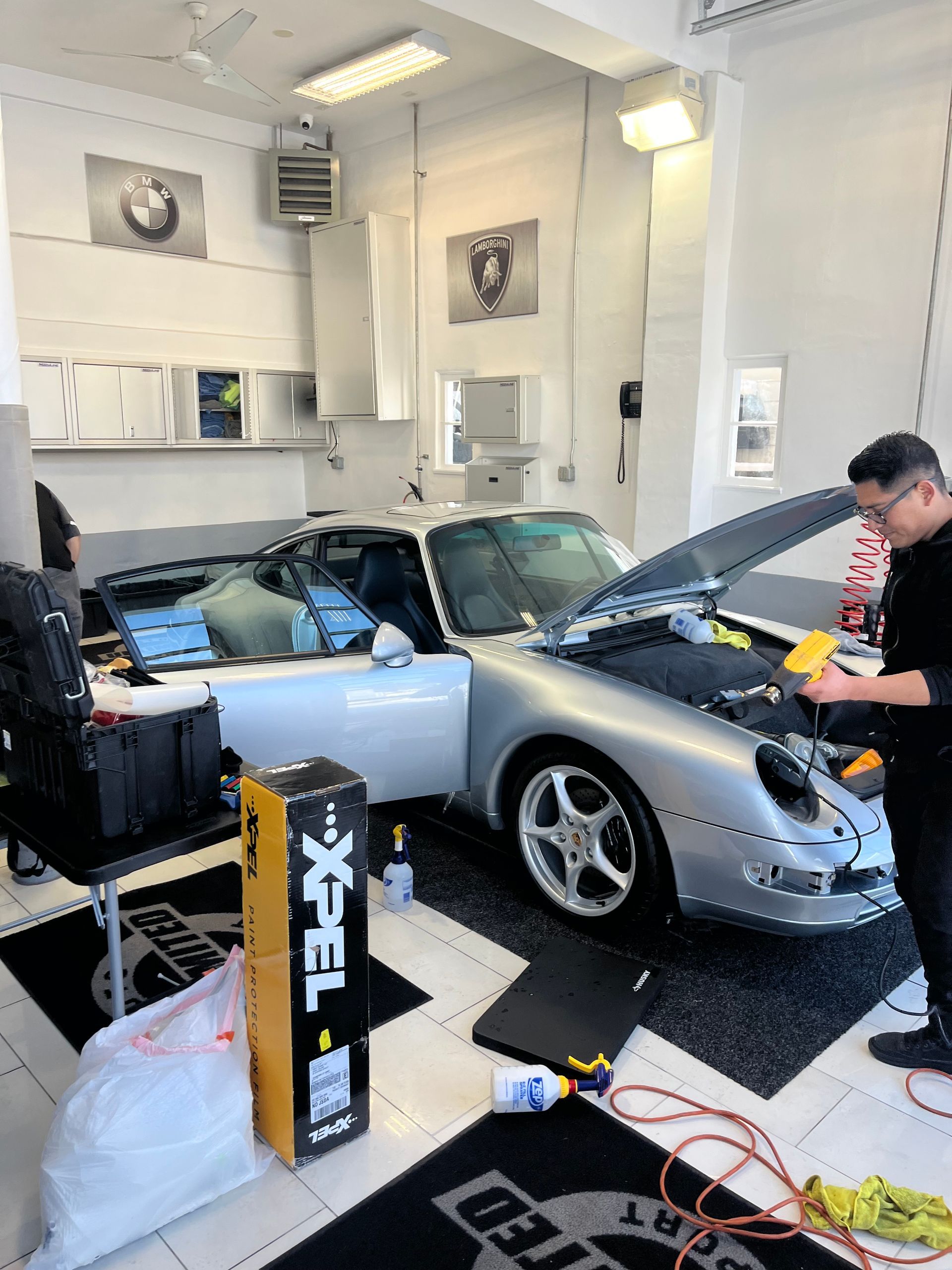 a man is working on a silver car in a garage .