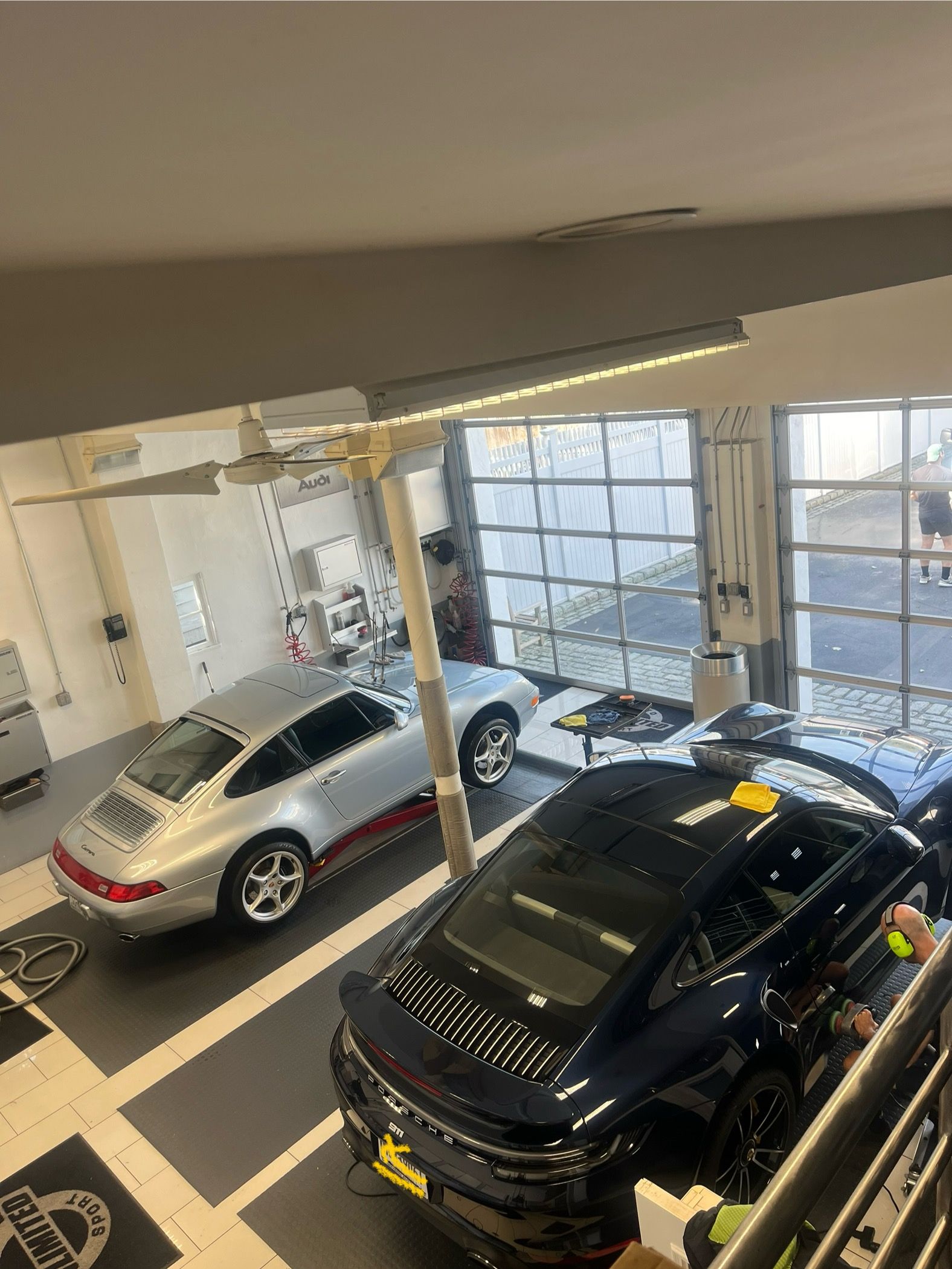 Two parked cars inside a bright showroom, a black SUV in front and a silver hatchback behind.