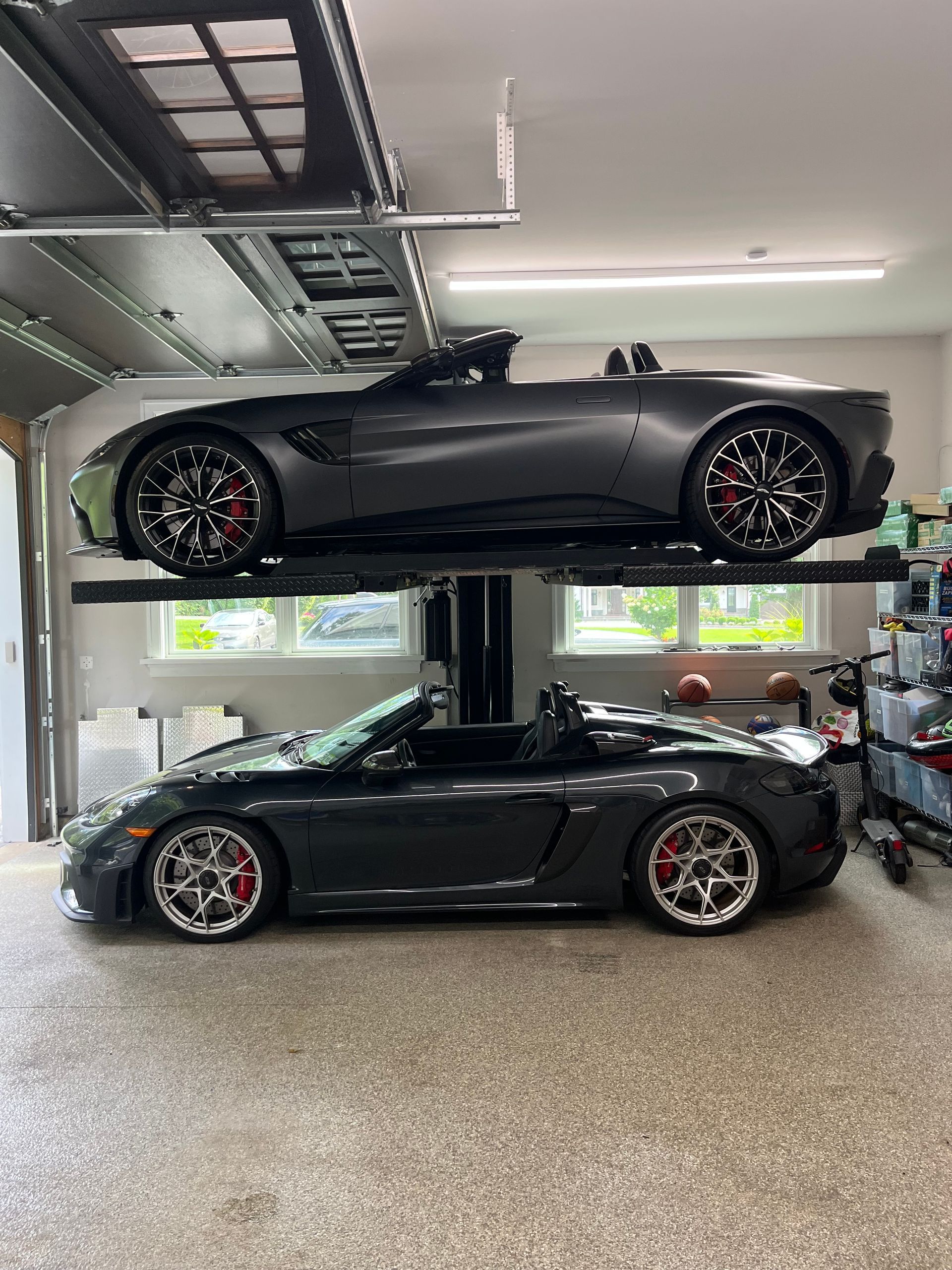 Two black sports cars parked one above the other in a garage