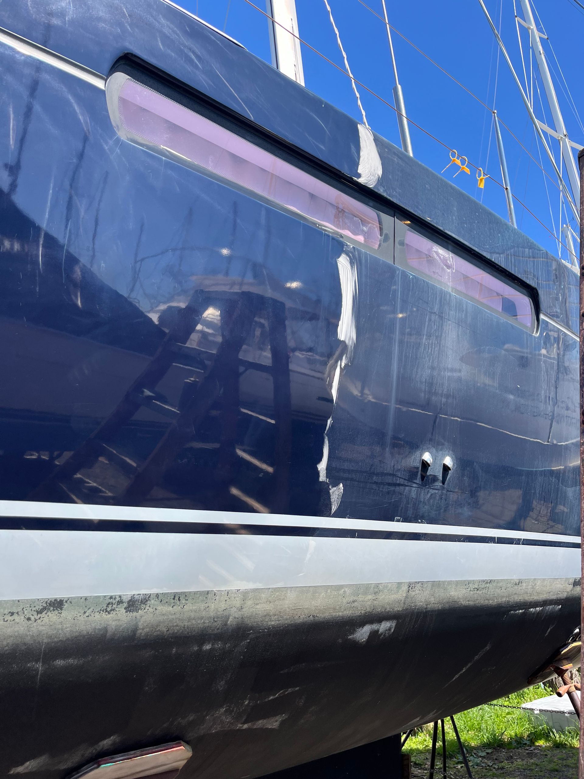 A boat with a hole in the side is parked in the grass