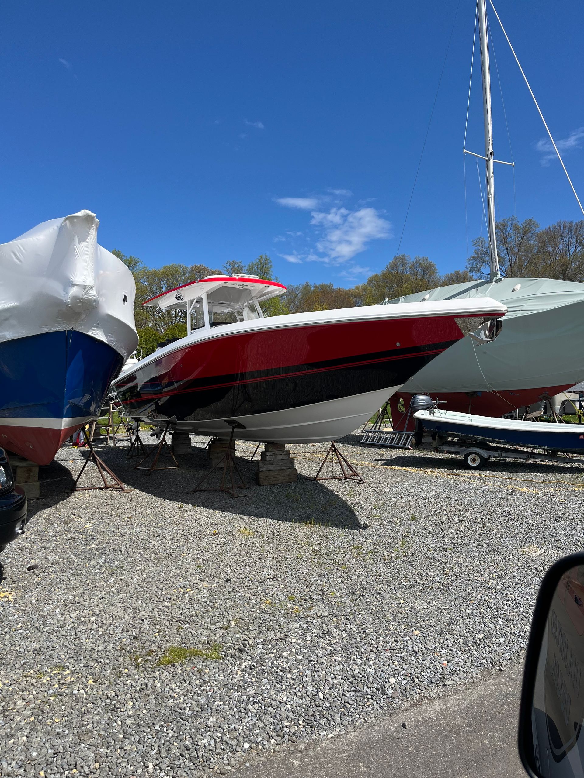 A group of boats are sitting on top of a gravel lot