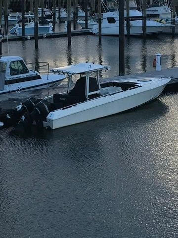 A white boat is docked at a marina next to a dock