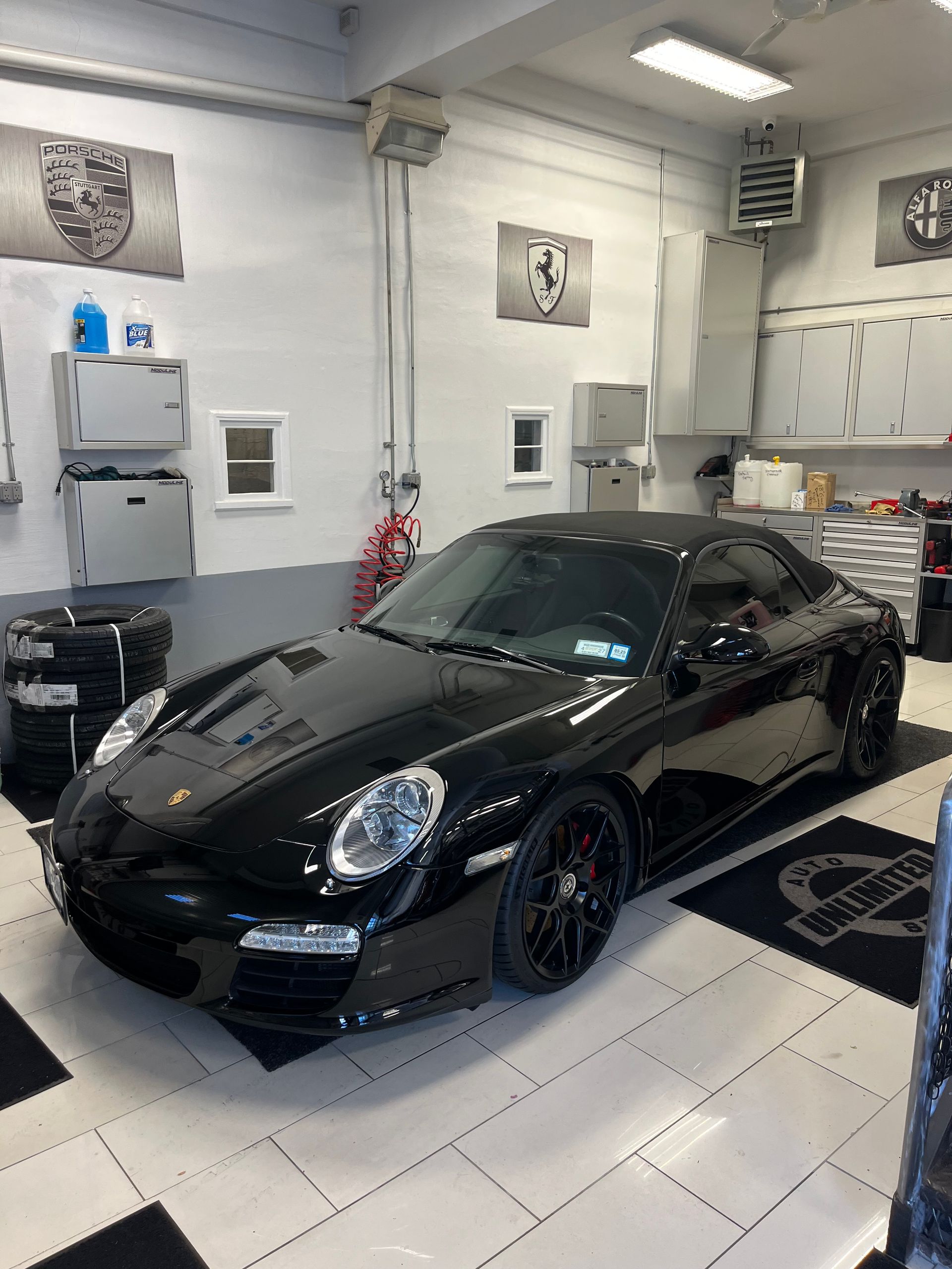 A black porsche 911 is parked in a garage.