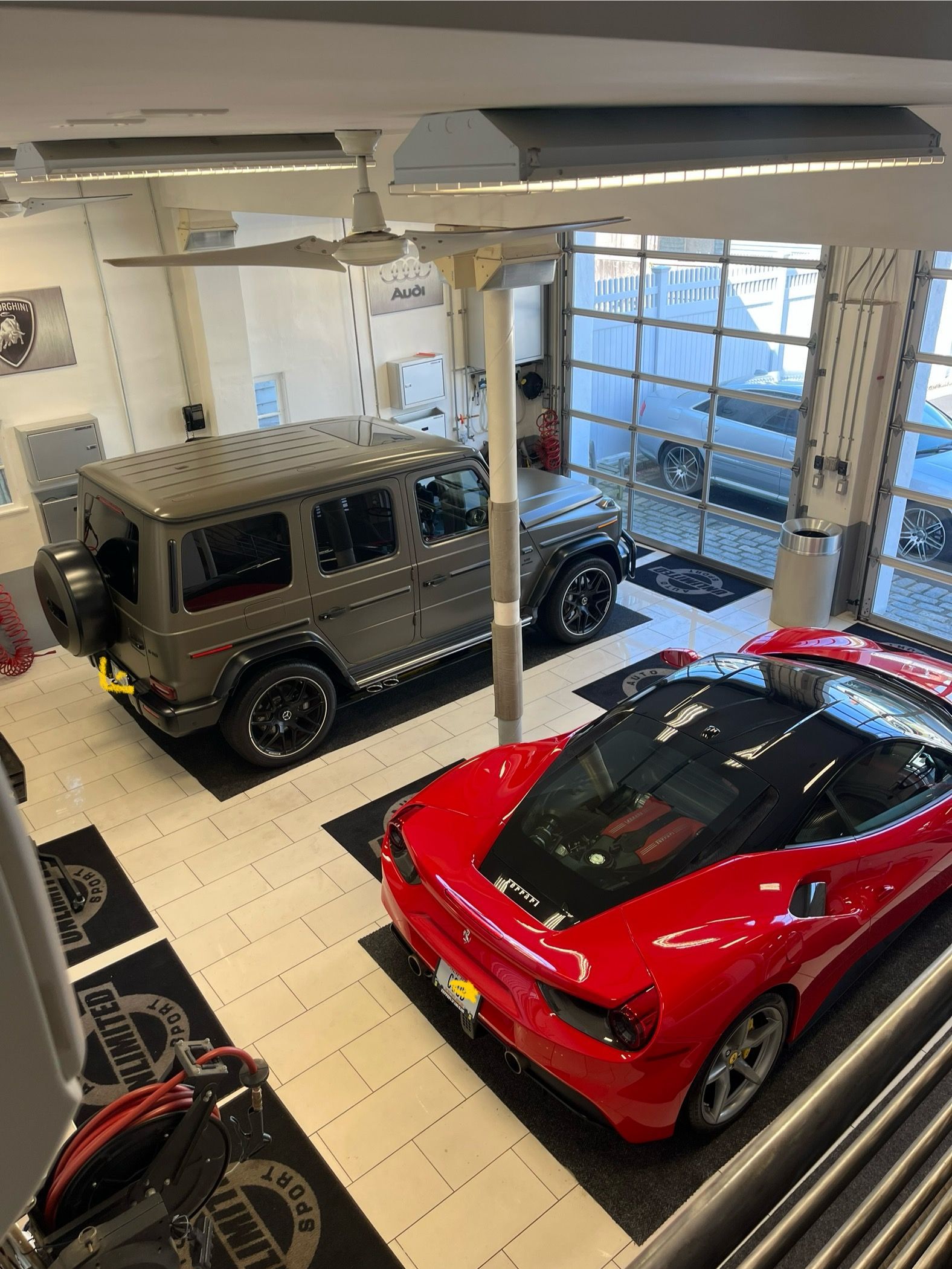 A jeep and a red sports car are parked in a garage.